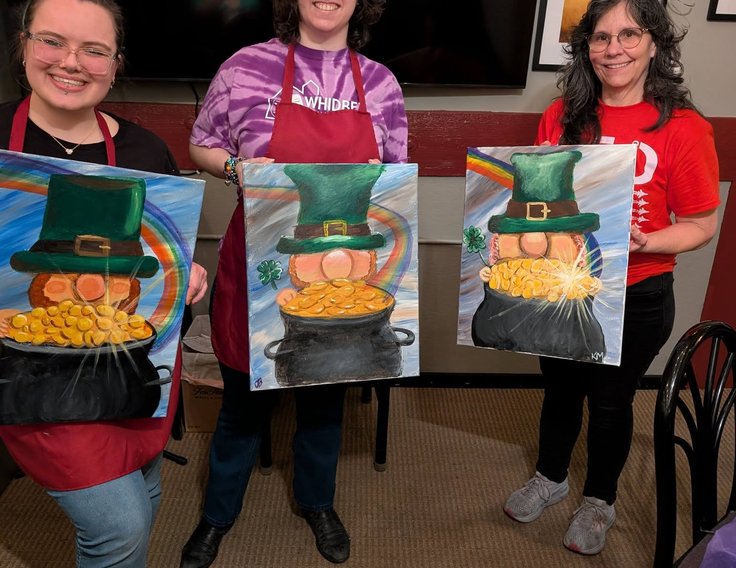 Three friends holding their finished paintings