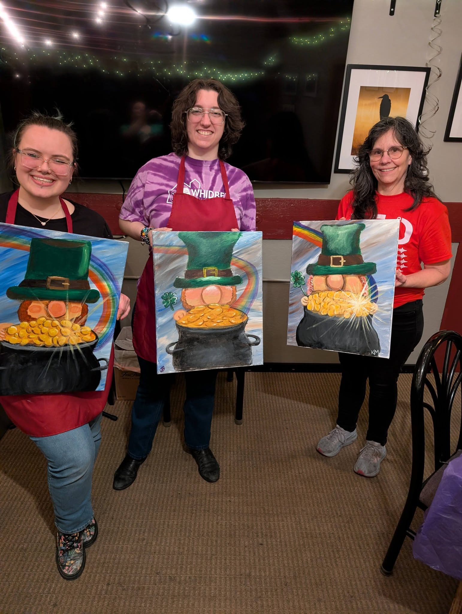 Three friends holding their finished paintings