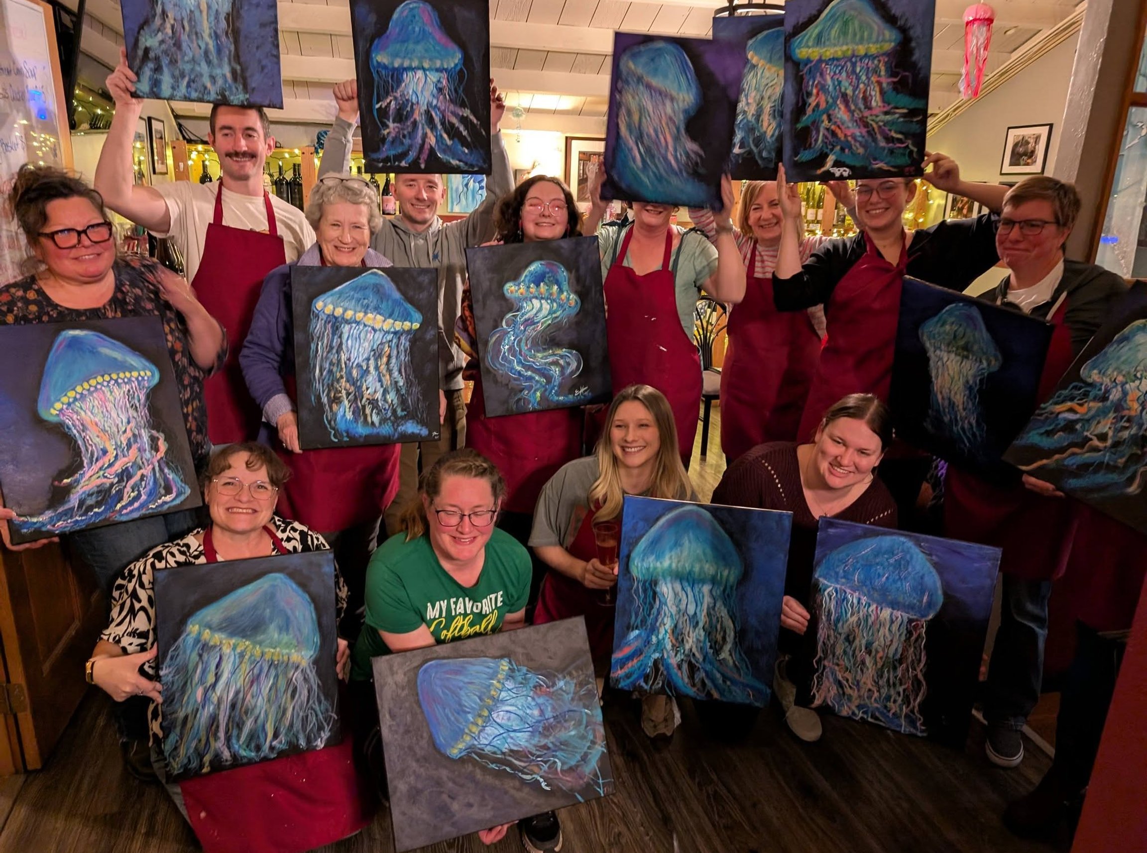 Group holding jellyfish paintings at a paint night