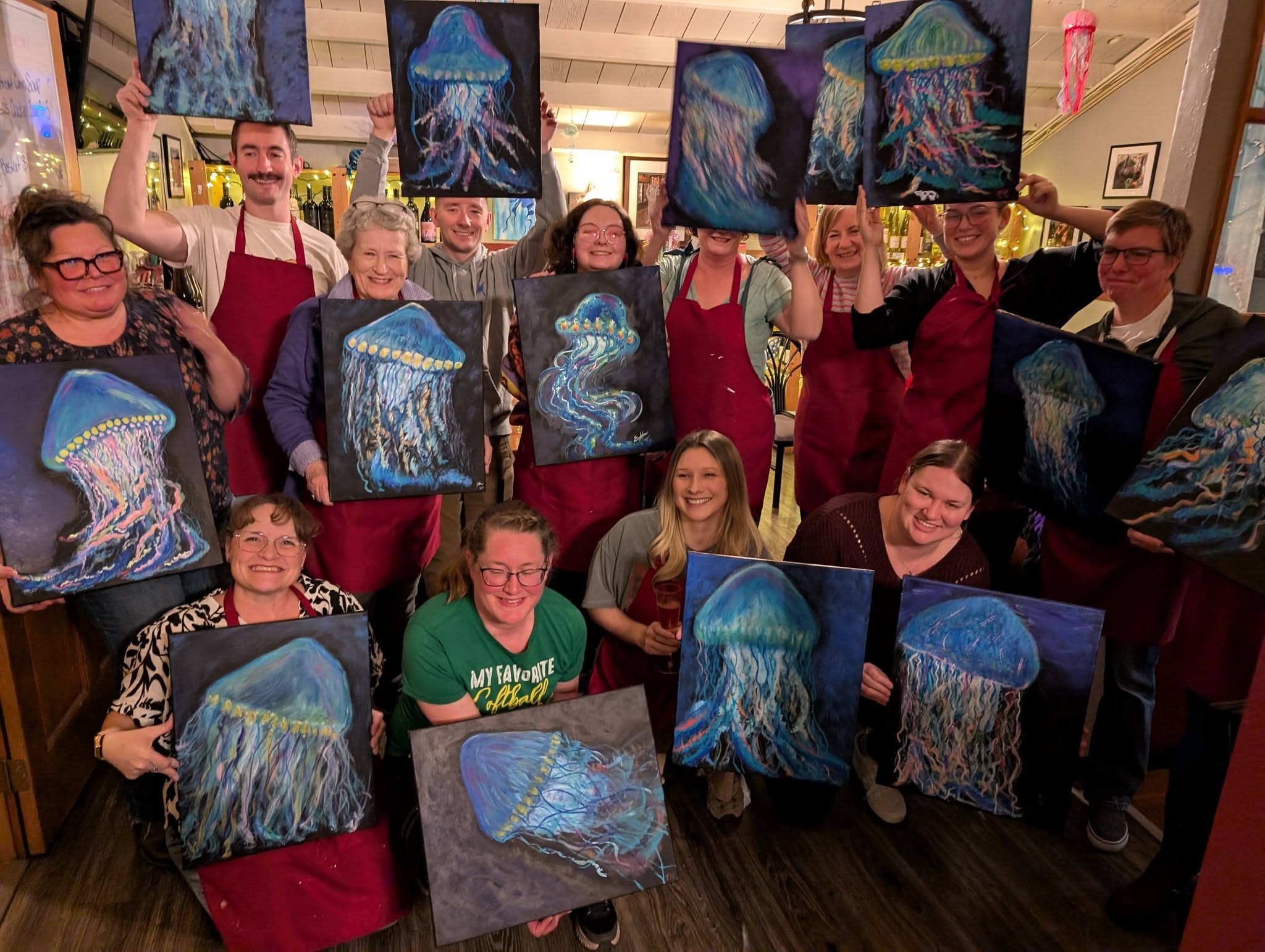 Group holding jellyfish paintings at a paint night