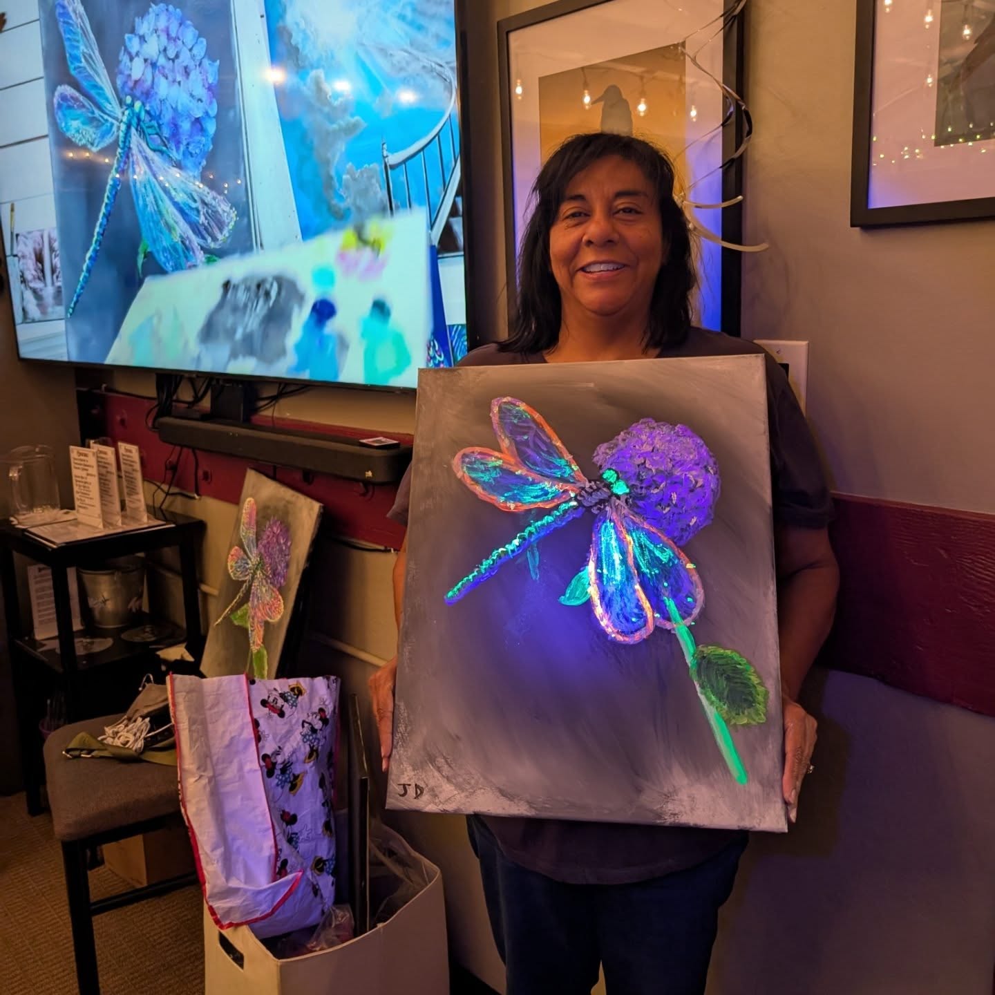 Guest holding a glowing dragonfly painting