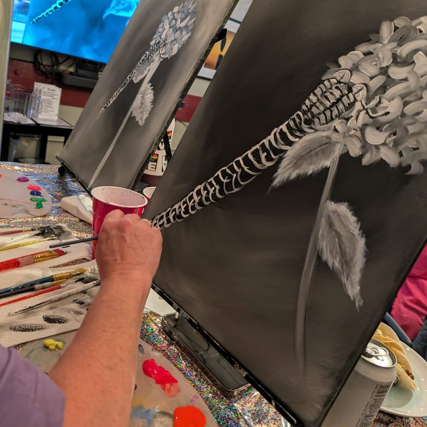 Hand painting a white flower on black canvas
