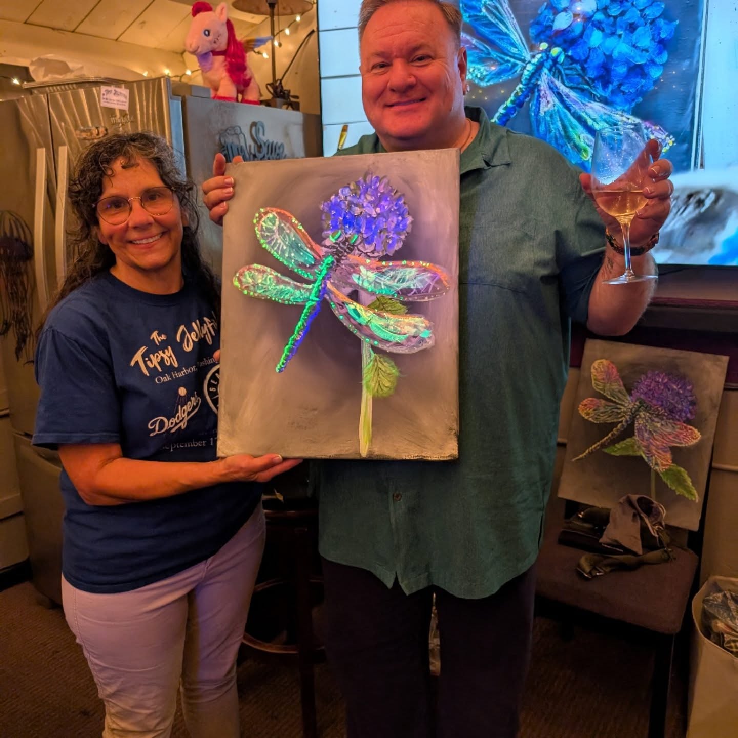 Two friends holding dragonfly paintings