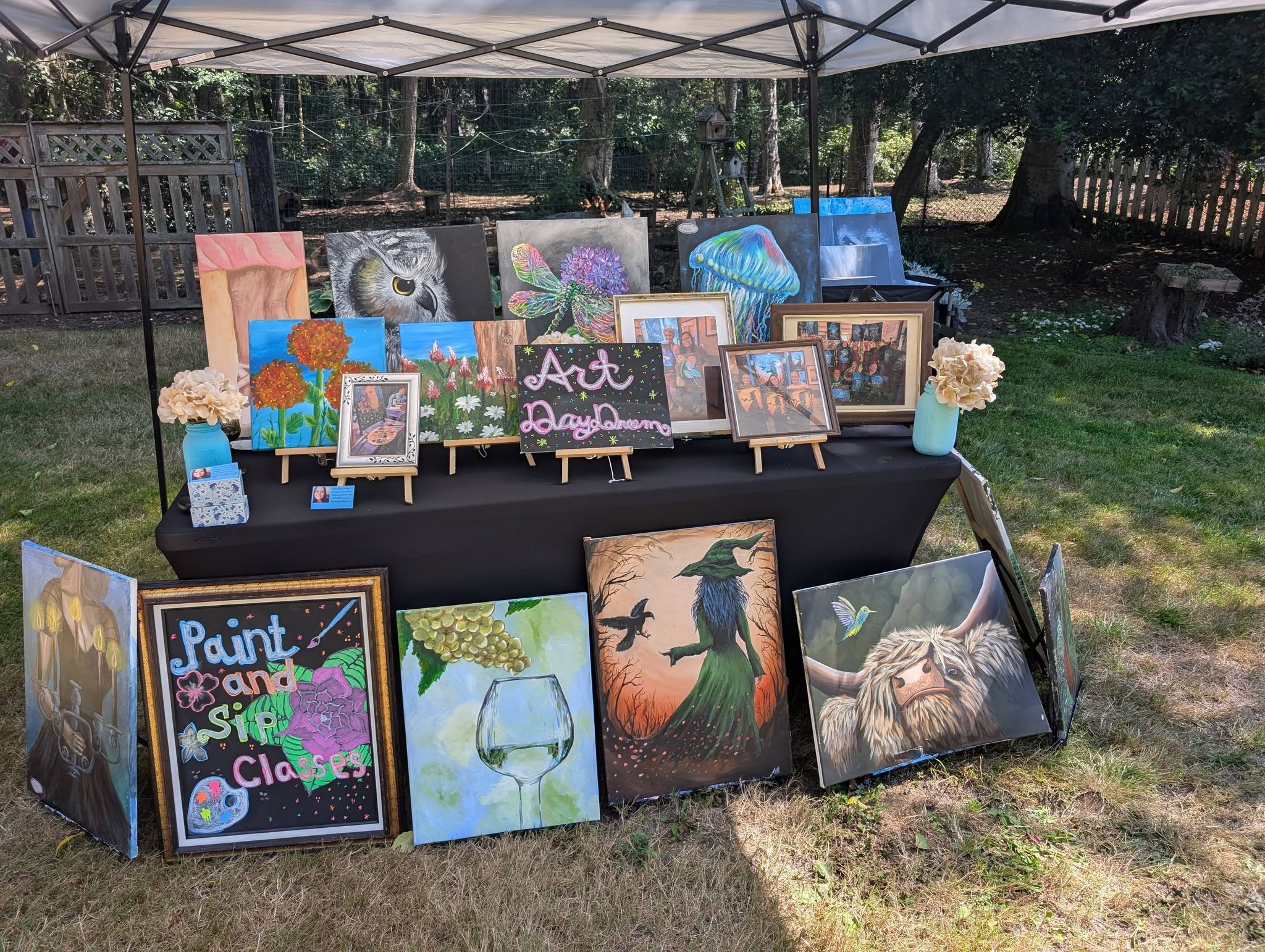 Table display of original paintings at an outdoor art market