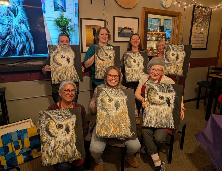 Group holding owl paintings at a paint night