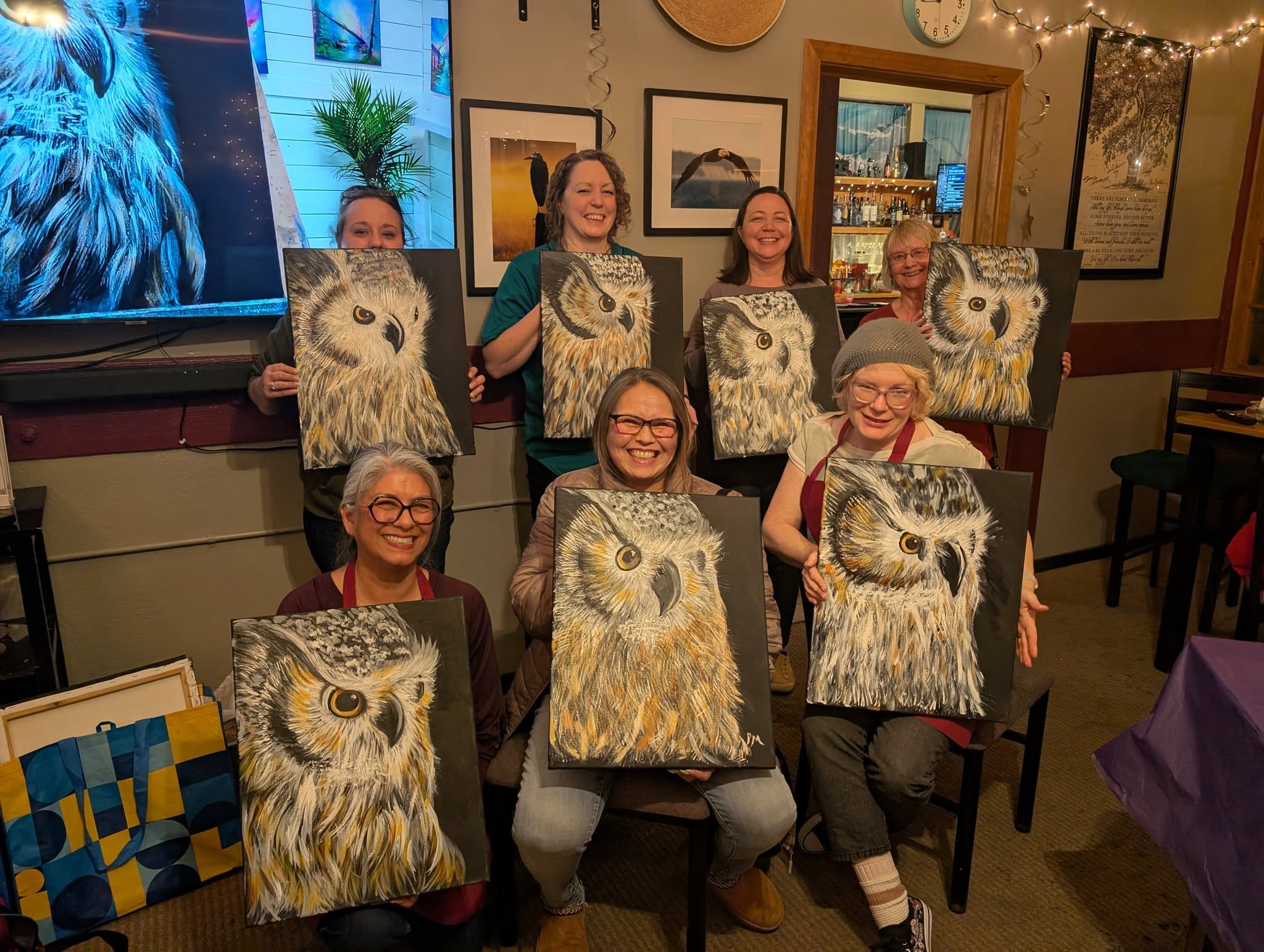 Group holding owl paintings at a paint night