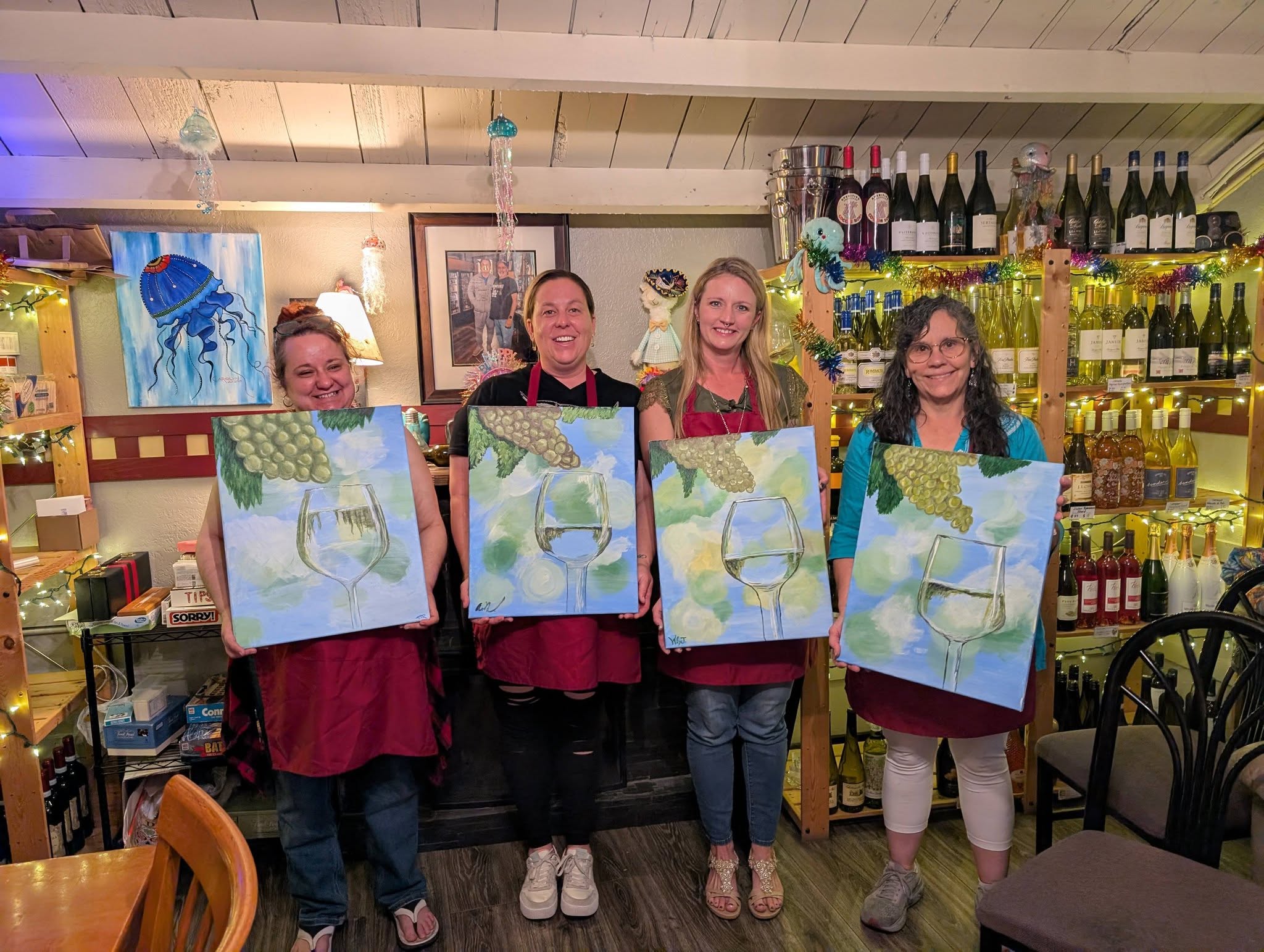 Paint and sip guests holding their paintings at a wine bar